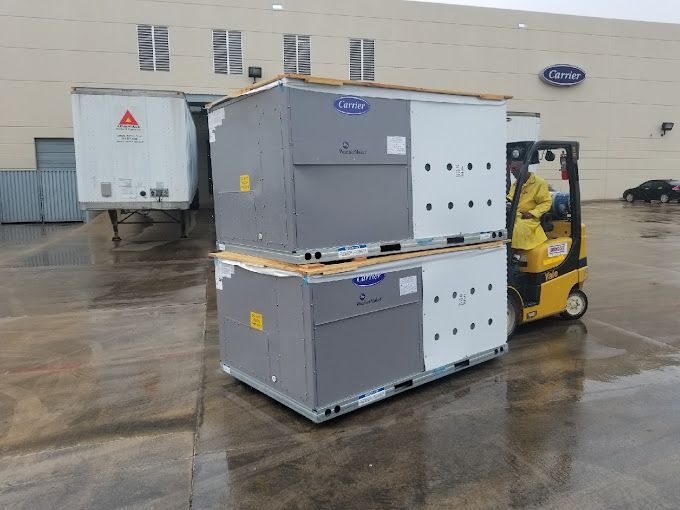 A forklift is carrying a stack of boxes in front of a building.