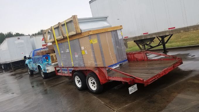 A truck is towing a trailer with boxes on it in a parking lot.