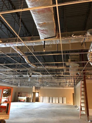 A large empty room with a lot of pipes hanging from the ceiling.