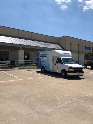 A white van is parked in a parking lot in front of a building.