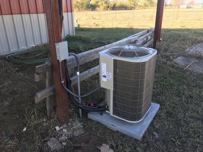An air conditioner is sitting on top of a concrete platform in the grass.