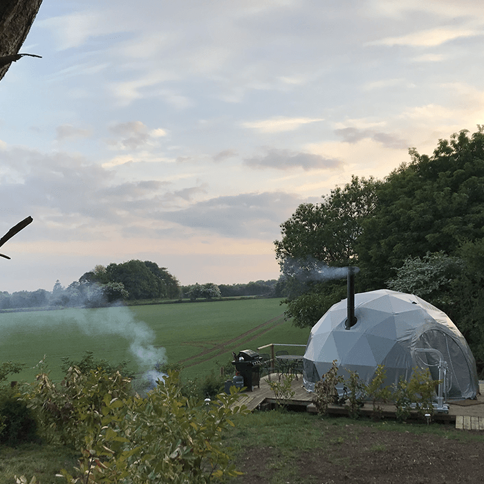 A dome tent is sitting in the middle of a field.