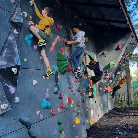 A group of kids are climbing a climbing wall