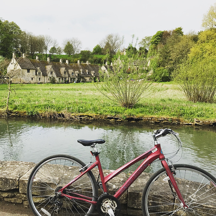 A red bicycle is parked on a stone wall next to a river.