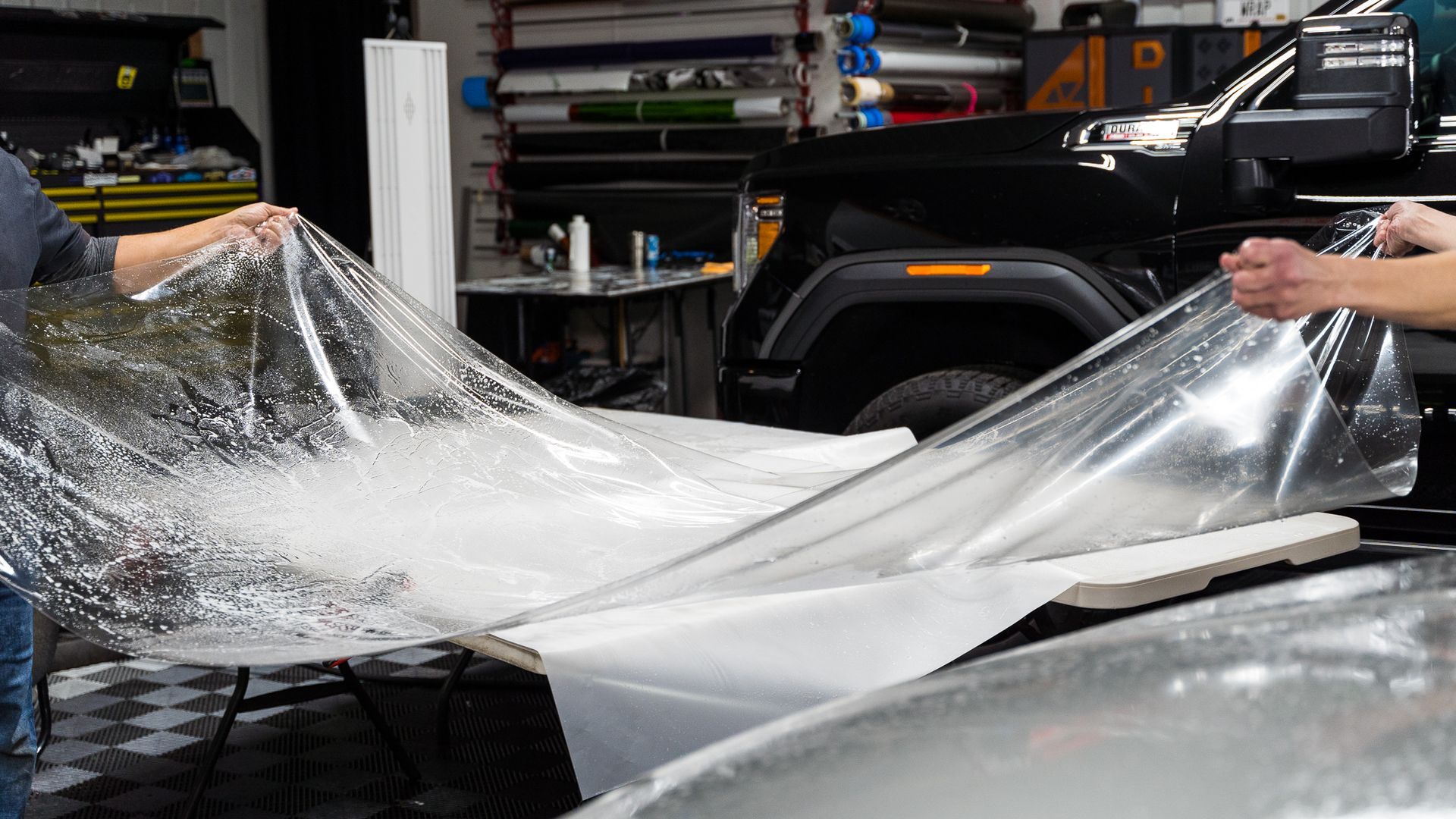 A man is wrapping a car with ppf wrap in a garage.