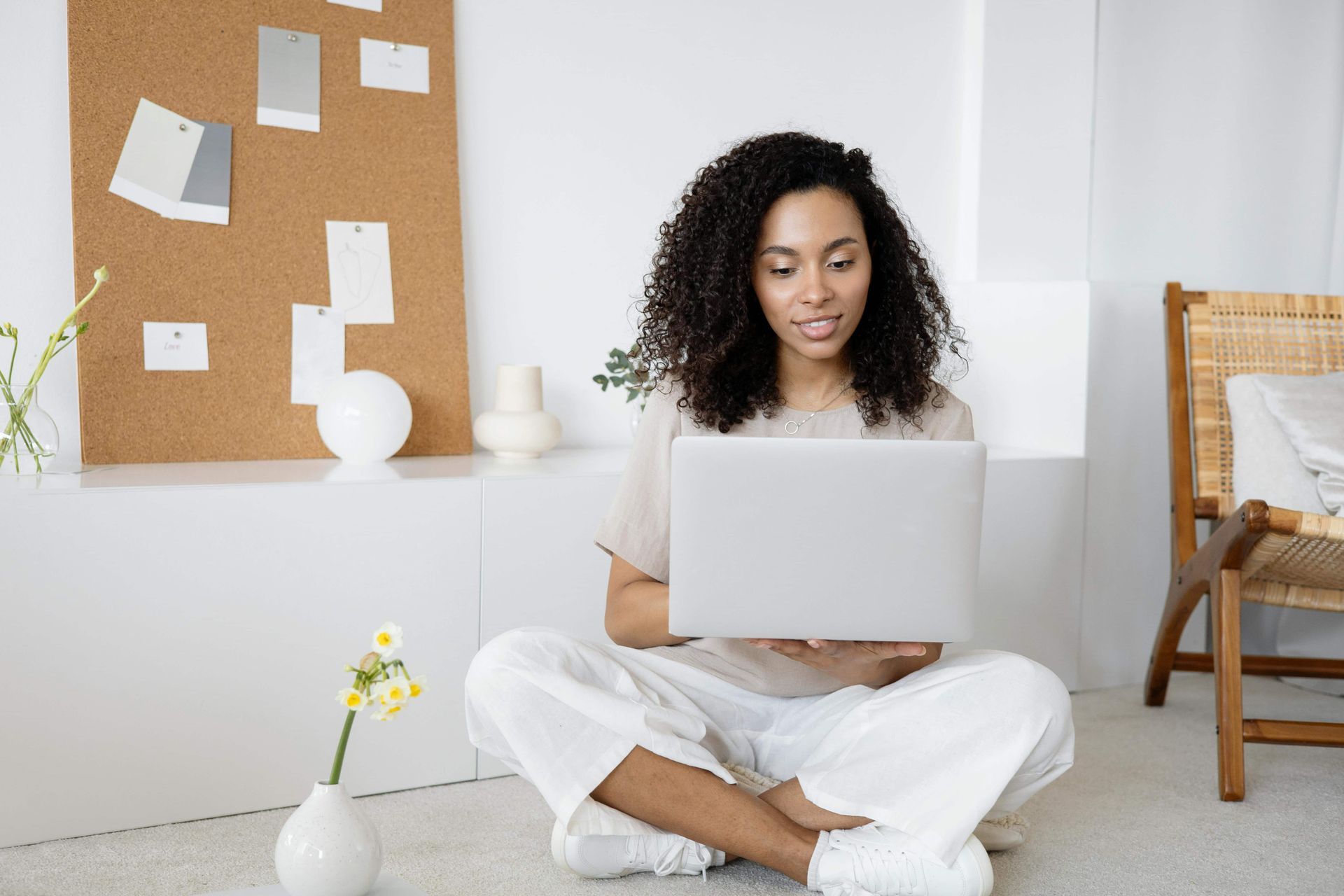 A woman is sitting on the floor using a laptop computer.