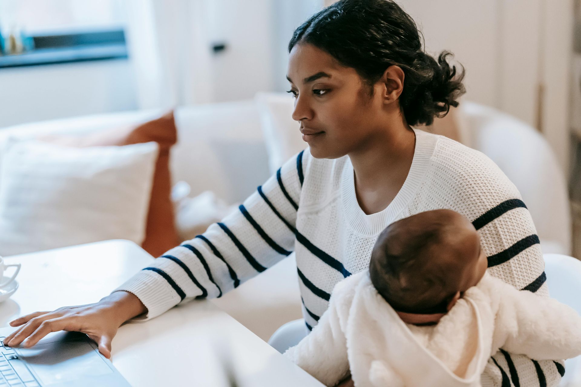 mum holding a baby and working on her computer at the same time