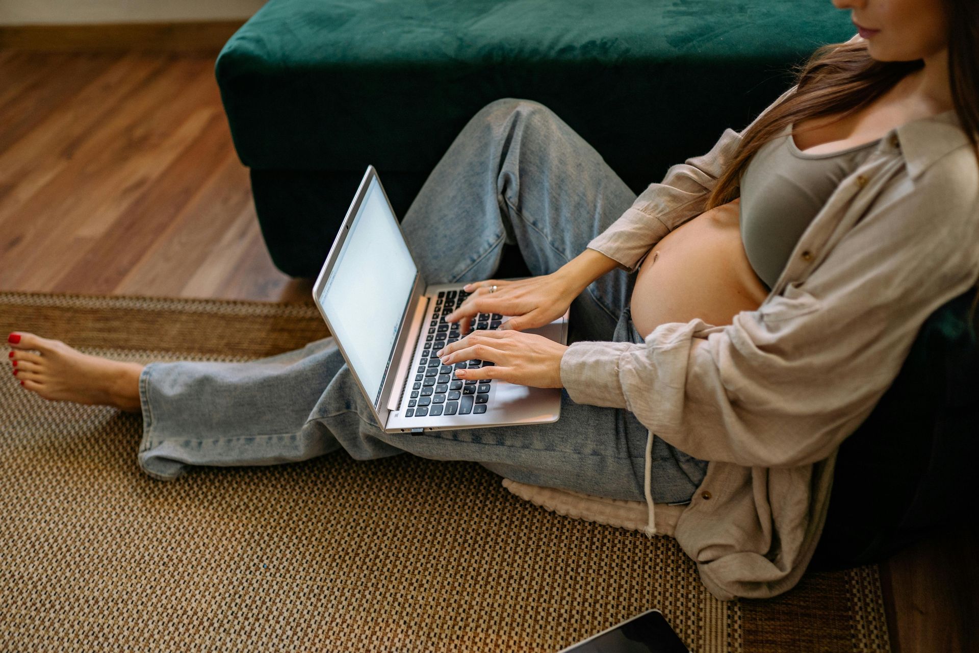 a pregnant woman sitting on the floor with her computer - a mom managing a business in Toronto 