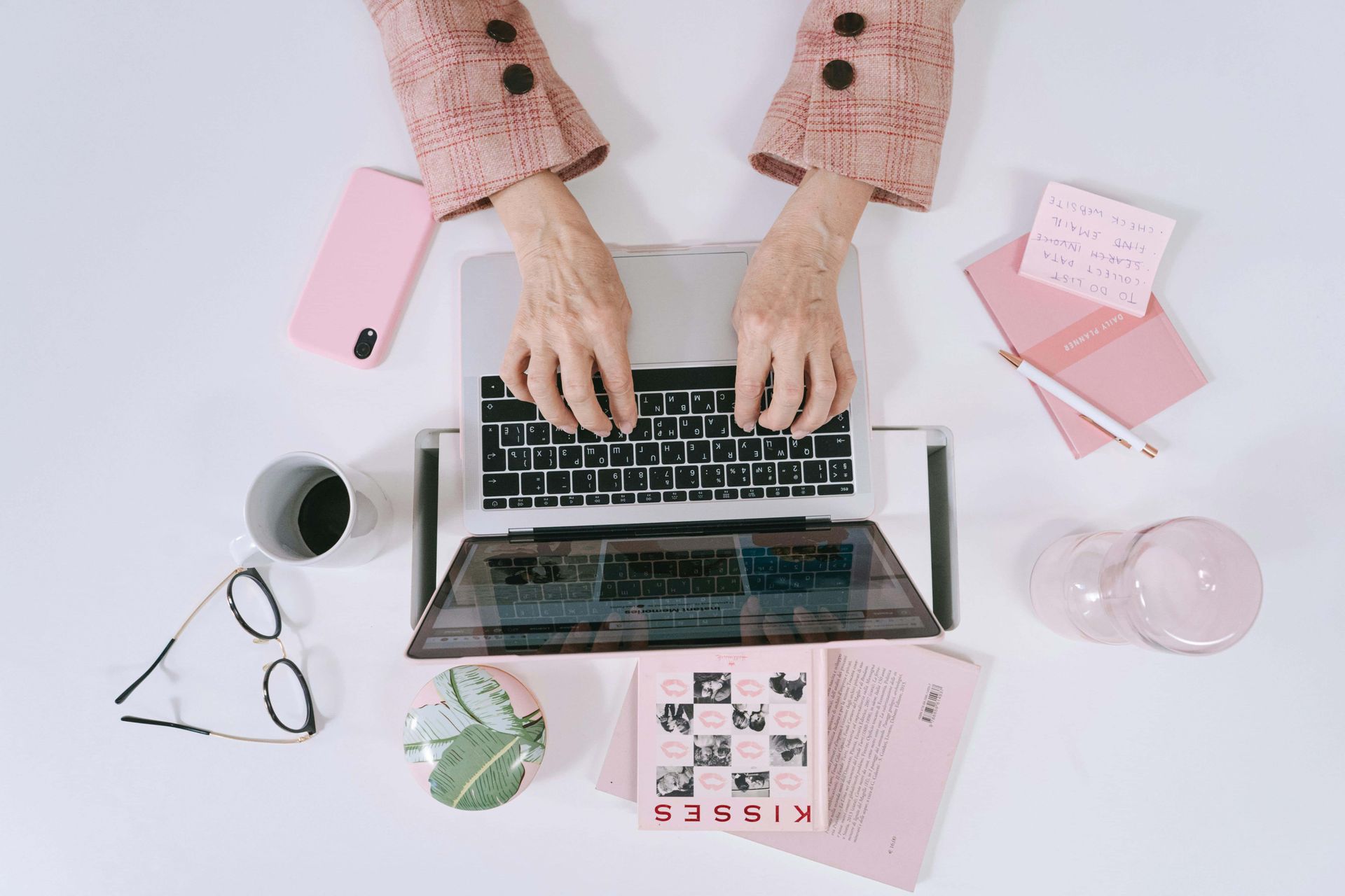 A woman is typing on a laptop computer at a desk.