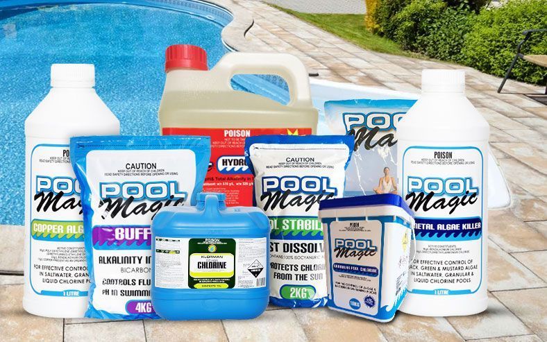 A variety of pool magic products are sitting on a patio next to a pool.