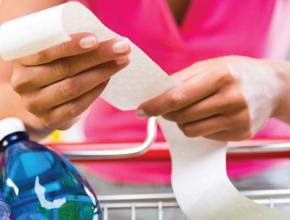 A woman in a pink shirt is holding a receipt in her hands
