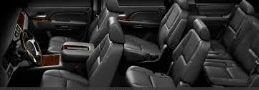 Interior view of a vehicle with black leather seating, including front bucket seats and rear bench seats. Wood trim accents the interior.