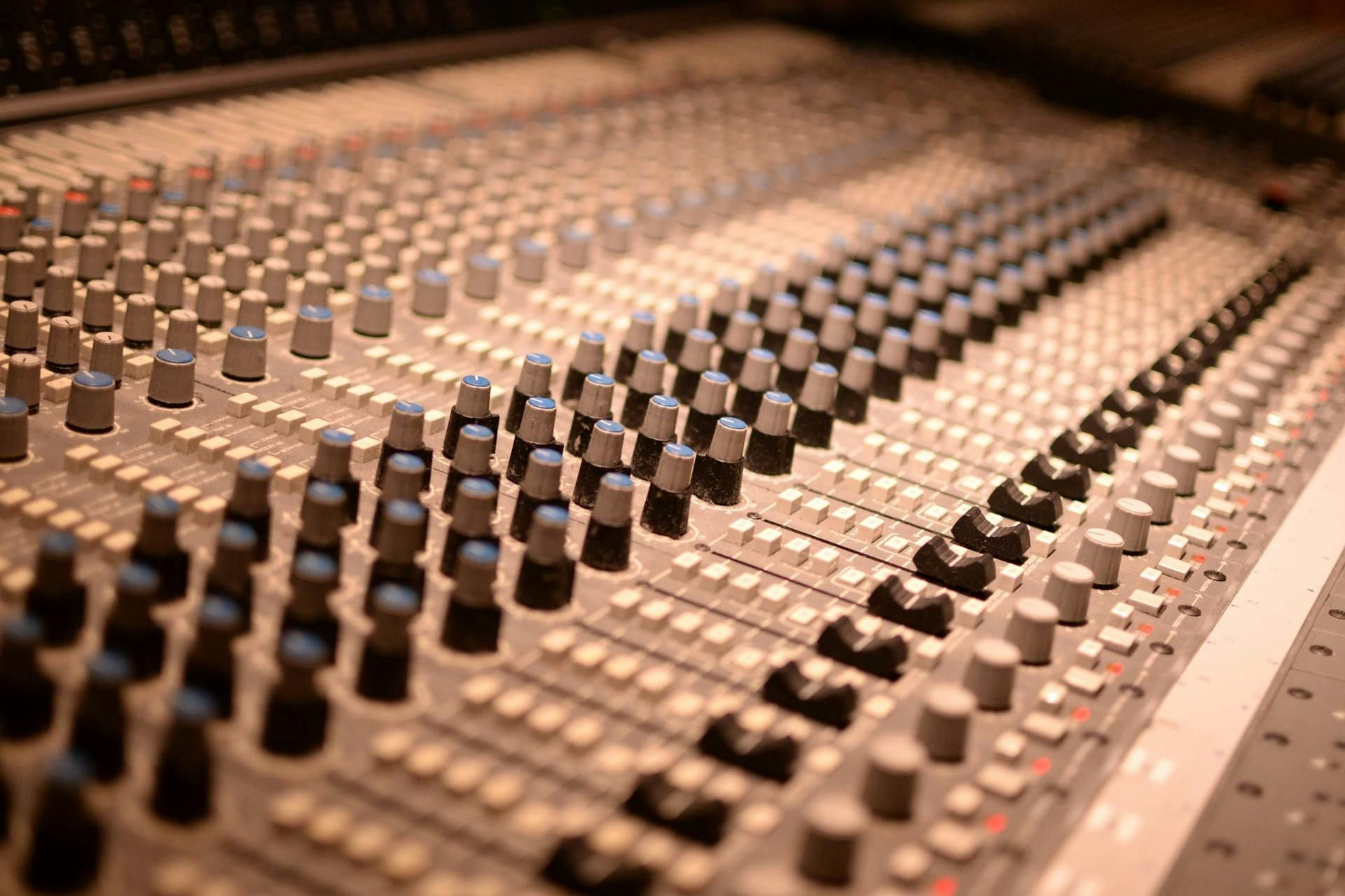 A close up of a sound board with a lot of knobs and buttons.