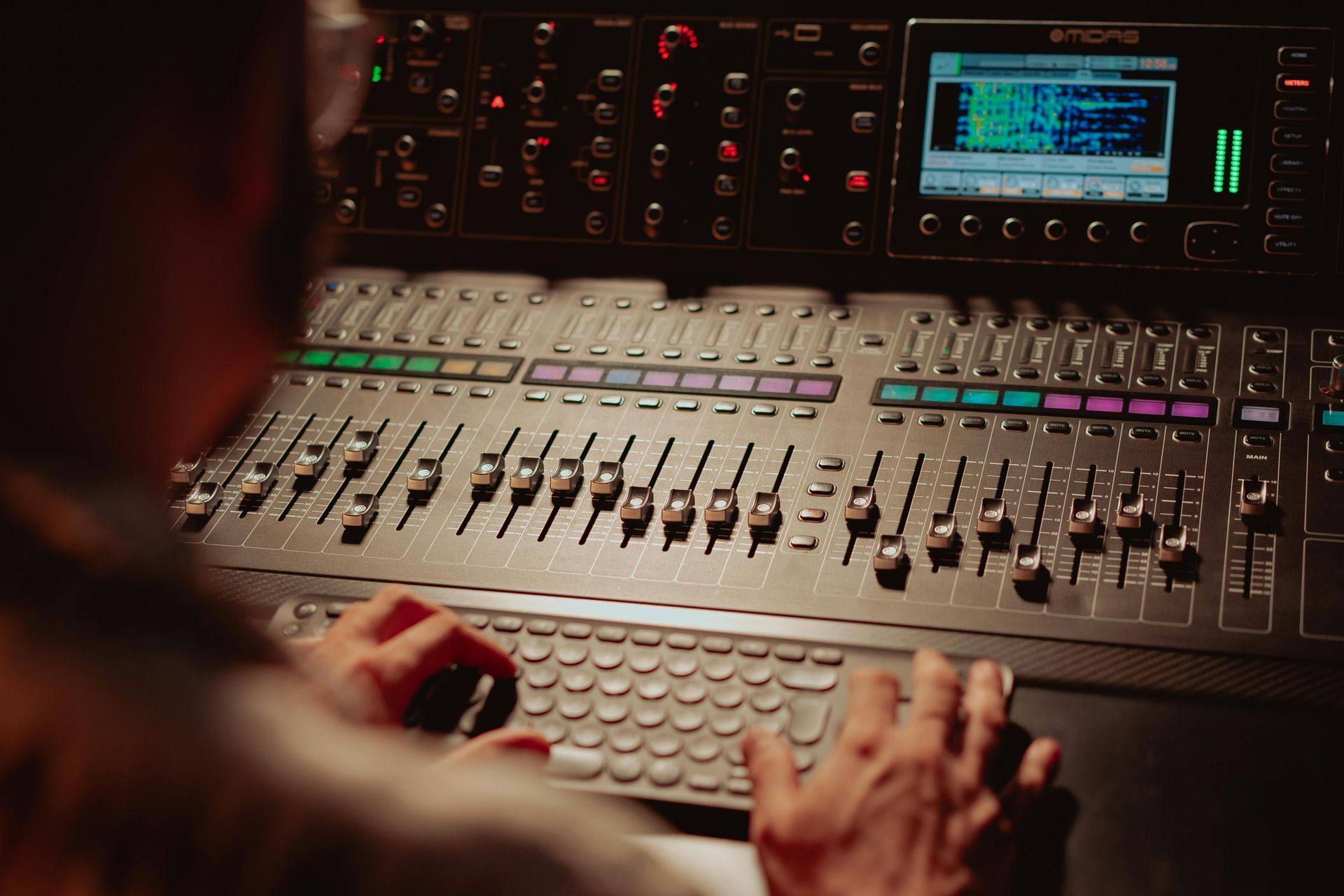 A person is typing on a keyboard in front of a mixer.