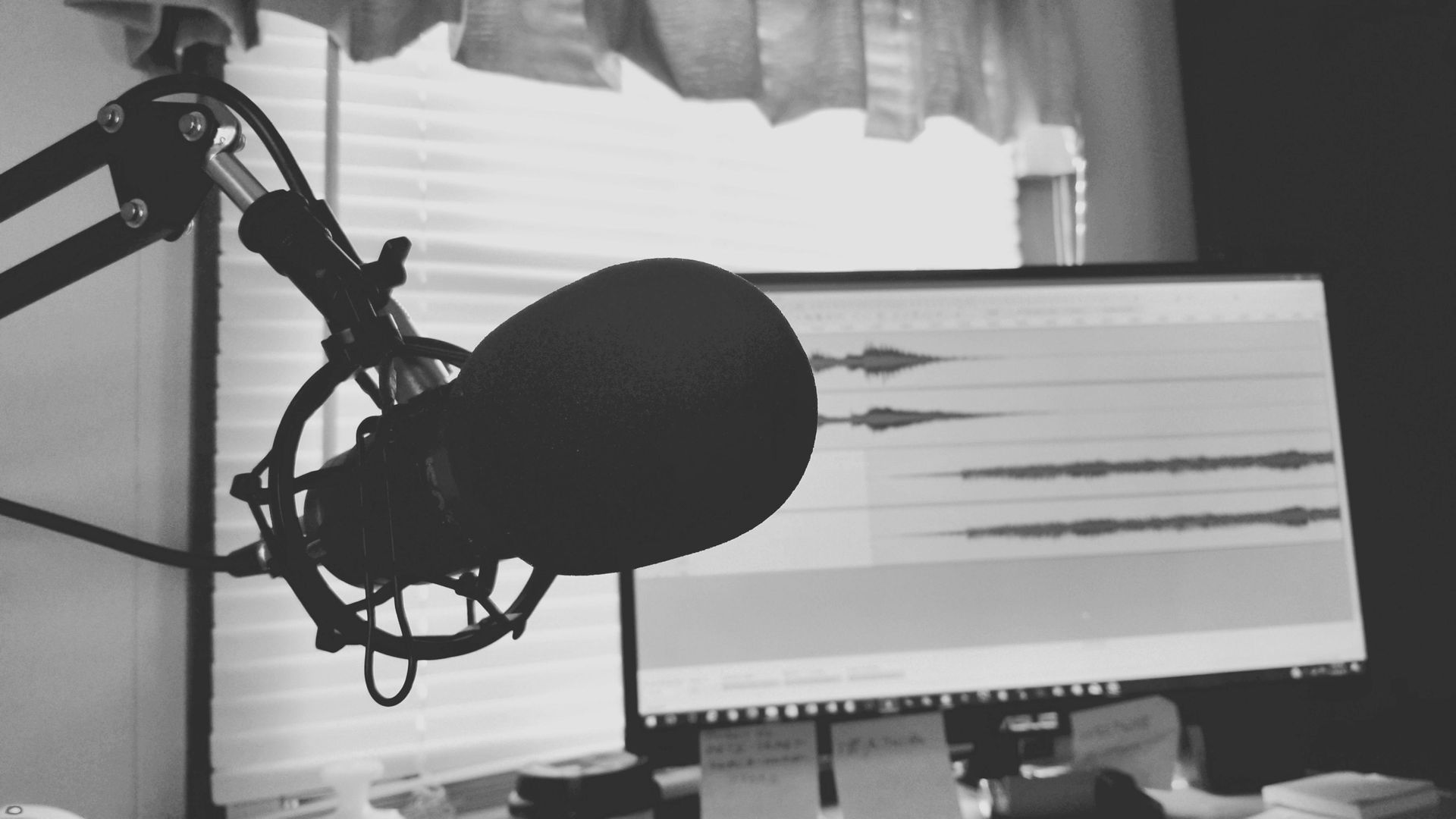 A black and white photo of a microphone and a computer monitor.