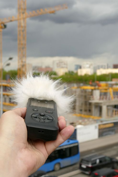 A person is holding a microphone in their hand in front of a construction site.