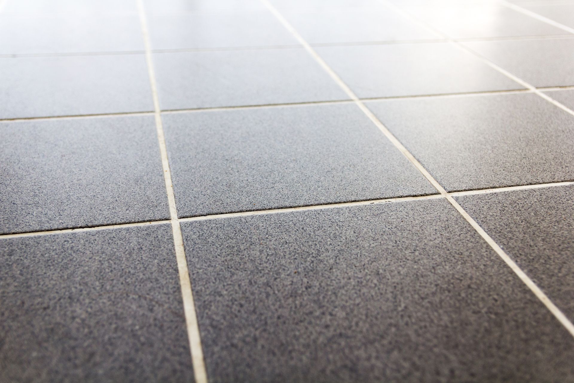 Gray tiled floor with white grout lines, viewed from a low angle.
