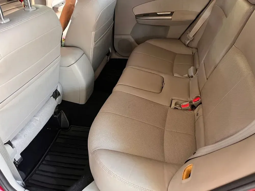 The back seat of a red car with tan leather seats.