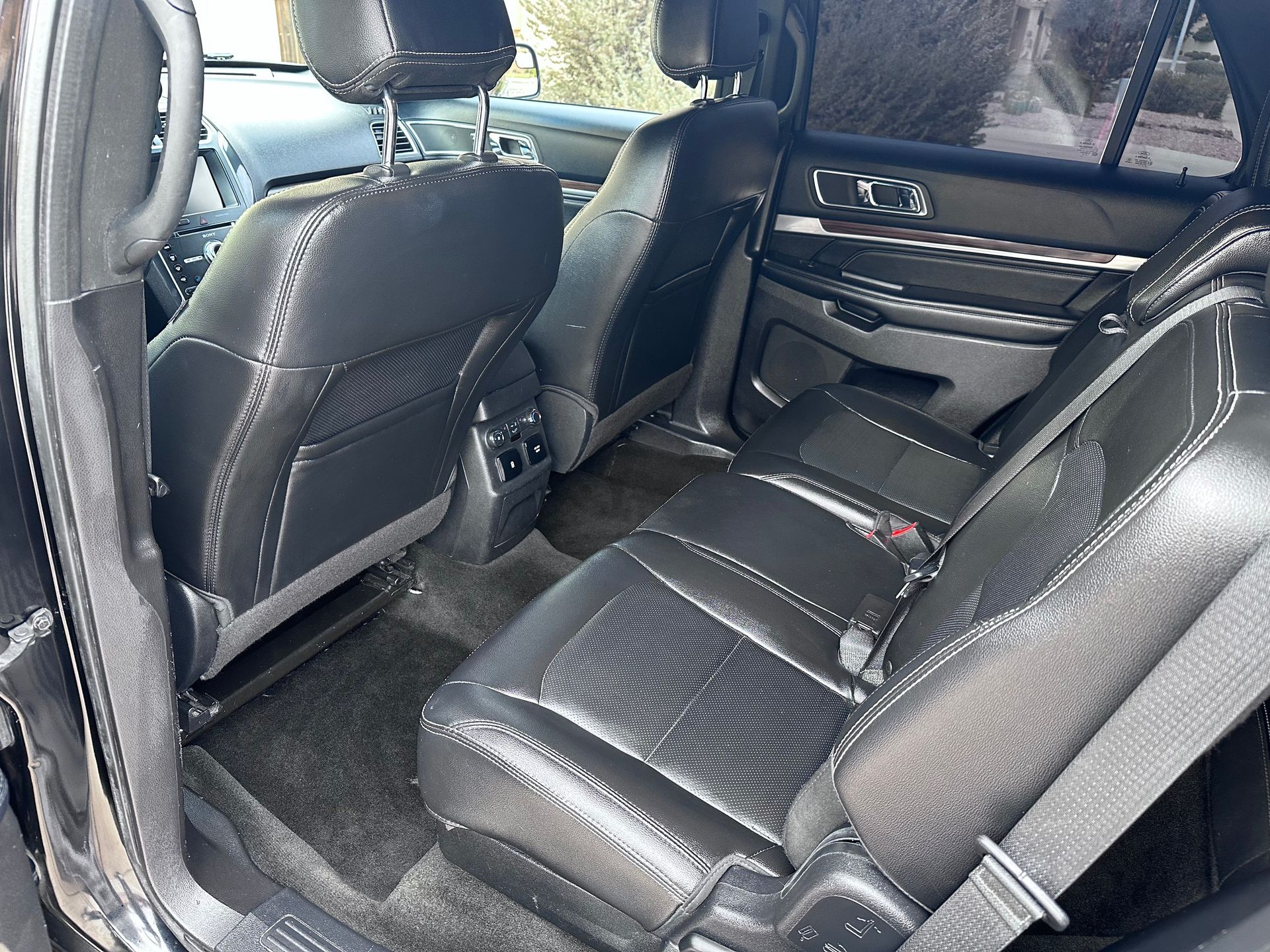 The rear seats of a ford explorer are black leather and have a seat belt.
