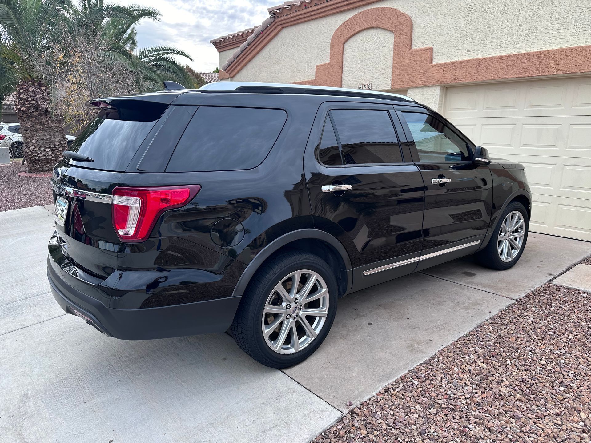 A black ford explorer is parked in front of a garage.
