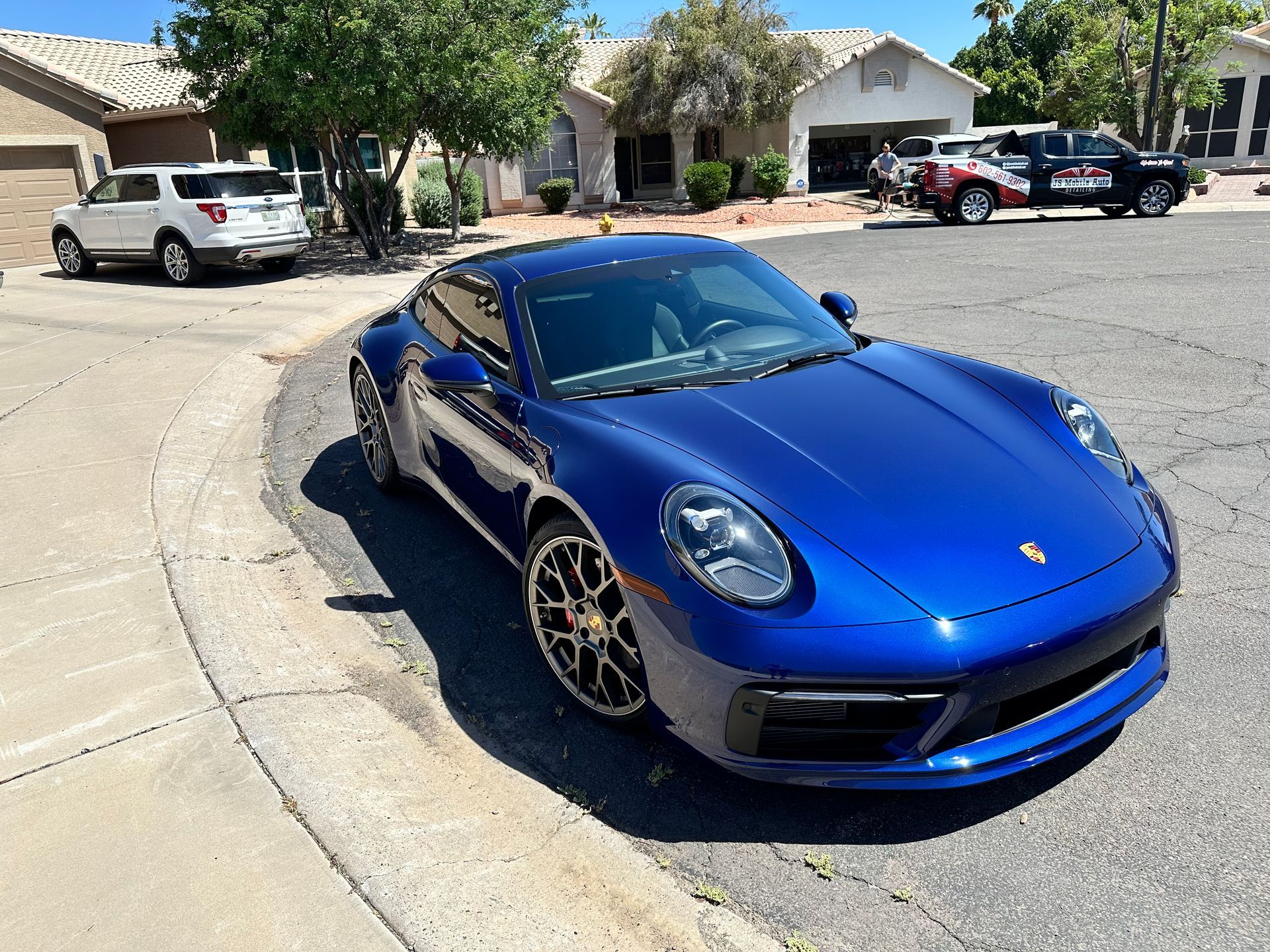 A blue porsche 911 is parked on the side of the road