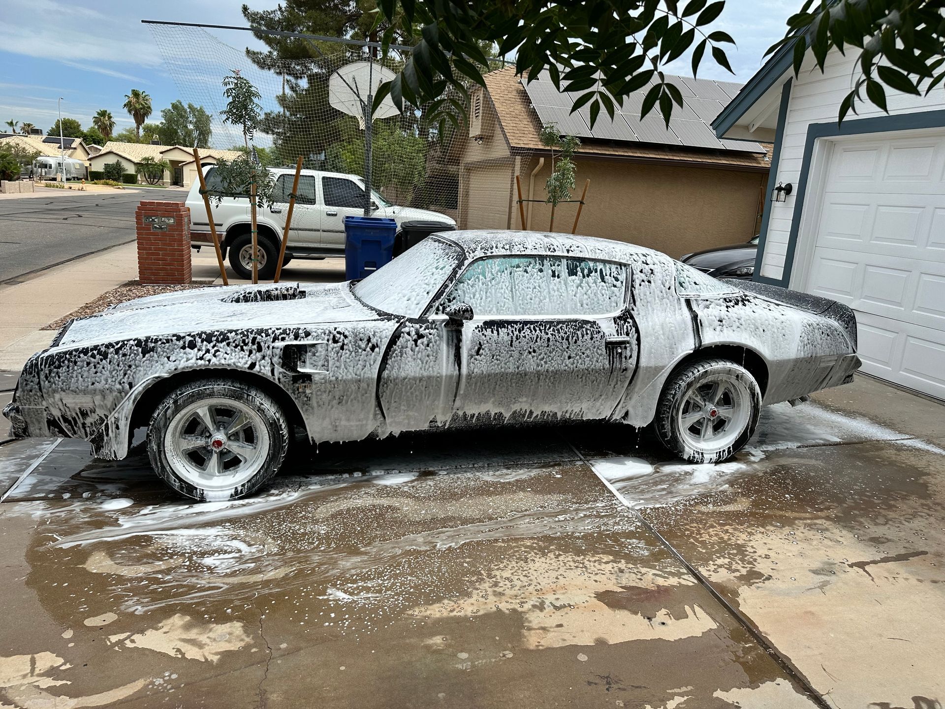 A car is covered in foam in a parking lot.