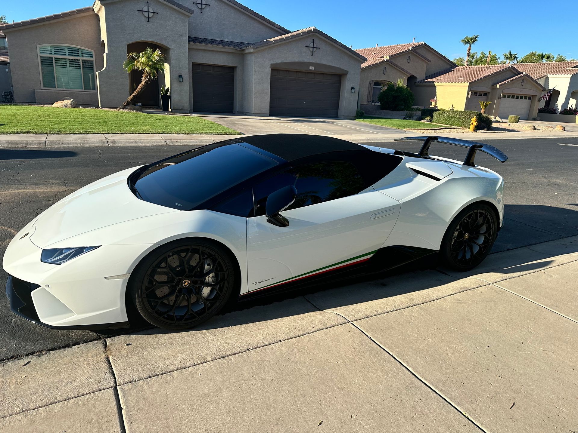 A white sports car is parked on the side of the road in front of a house.
