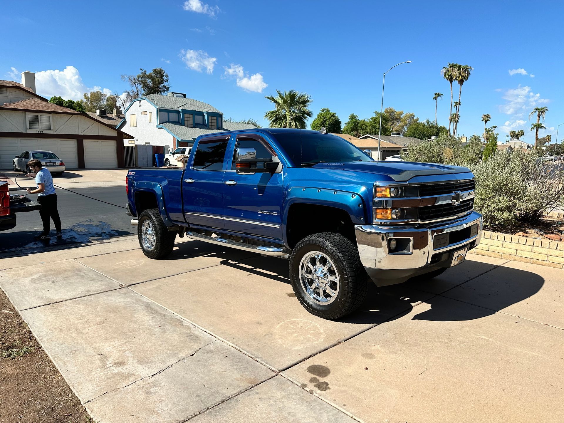 A blue truck is parked in a driveway in front of a house.