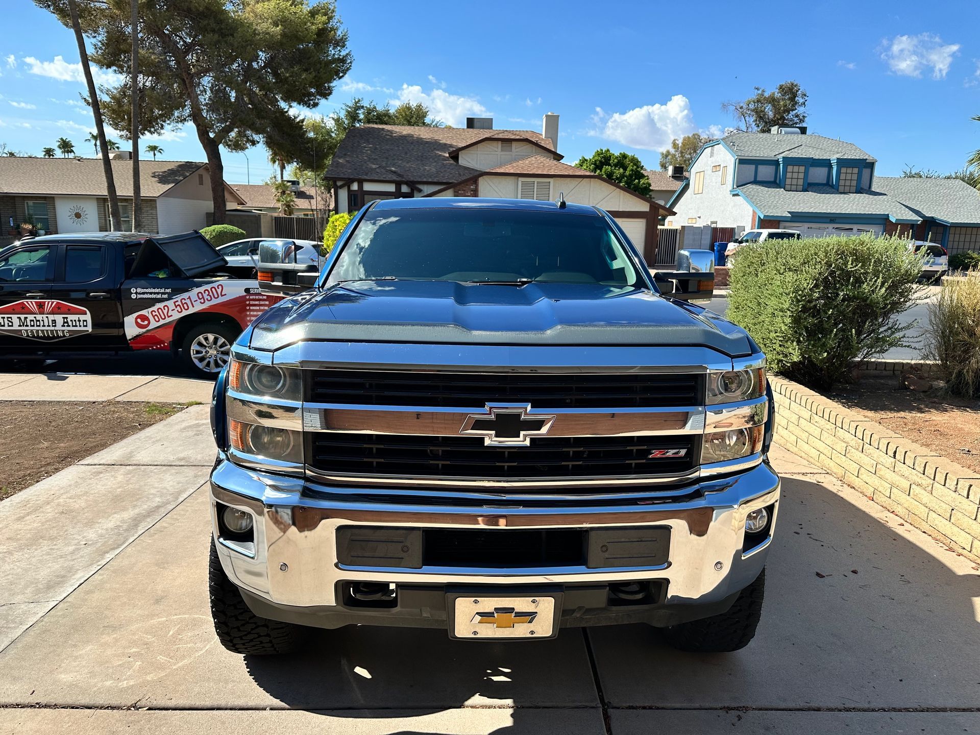 A silver truck is parked in a driveway in front of a house.