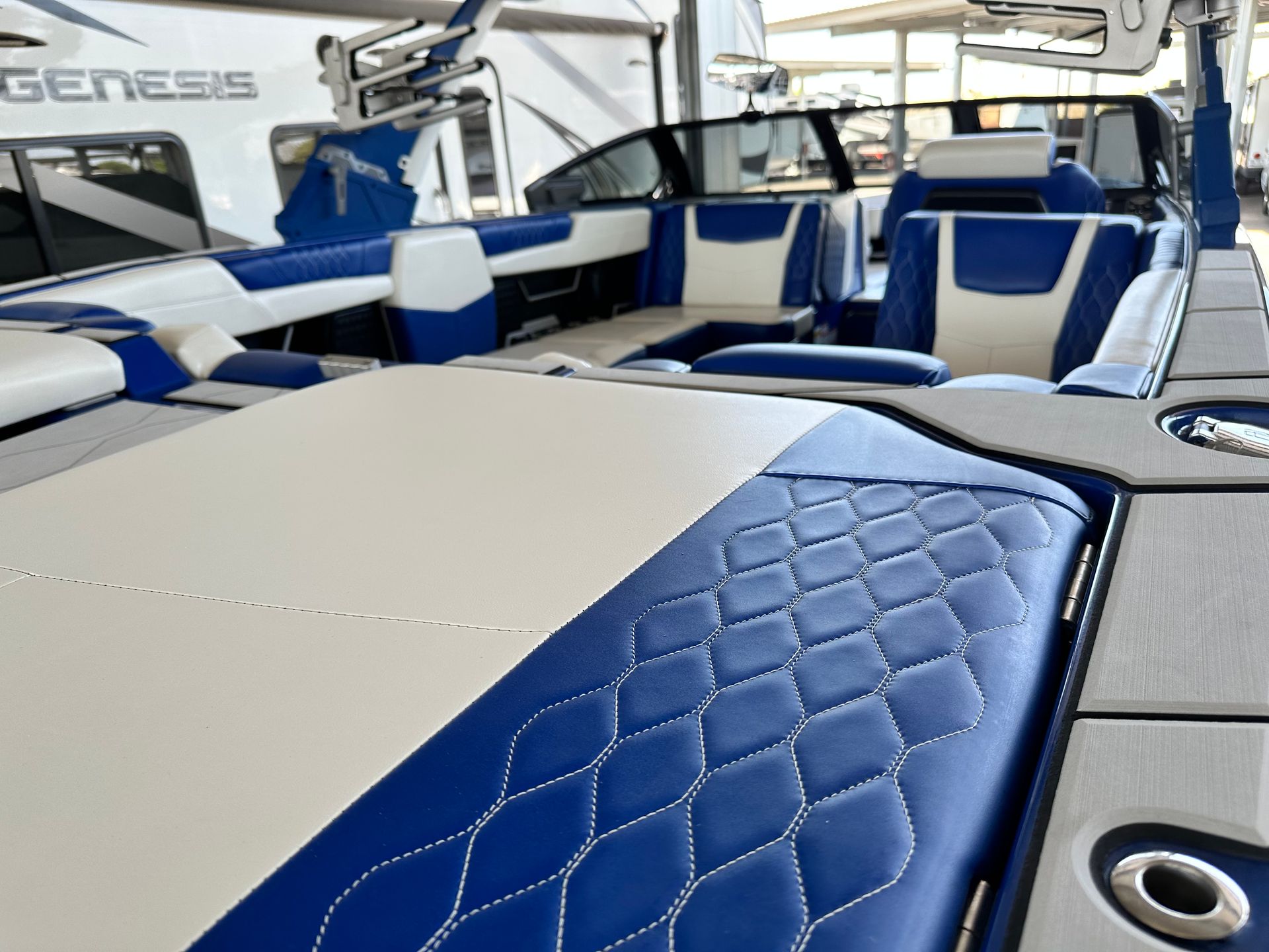 A blue and white boat with a genesis trailer in the background