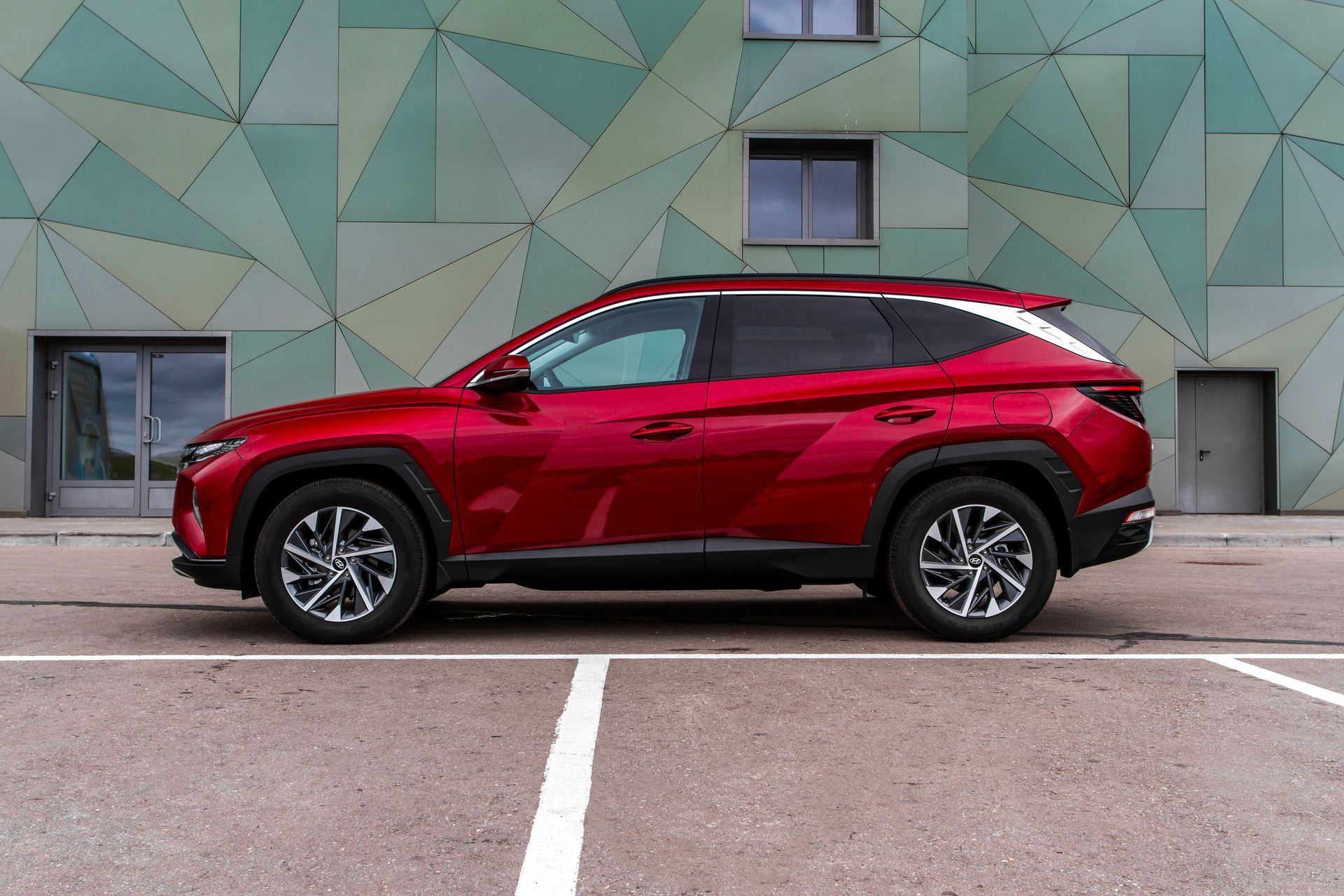 A red suv is parked in a parking lot in front of a building.