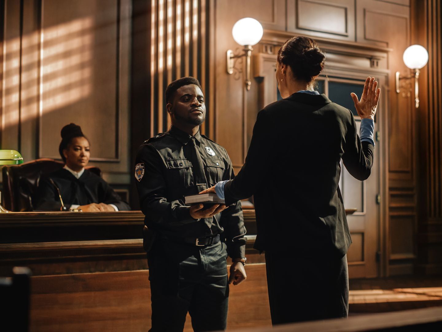 A police officer is giving a woman a bible in a courtroom.