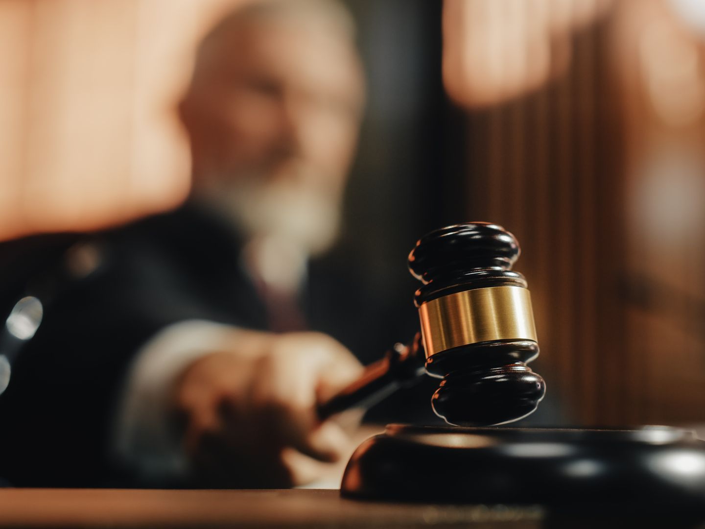 A judge is holding a wooden gavel in a courtroom.