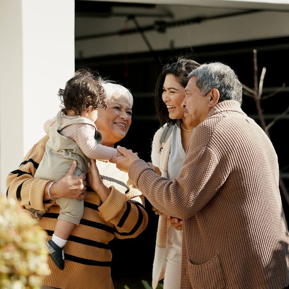 A woman is holding a baby while talking to two men