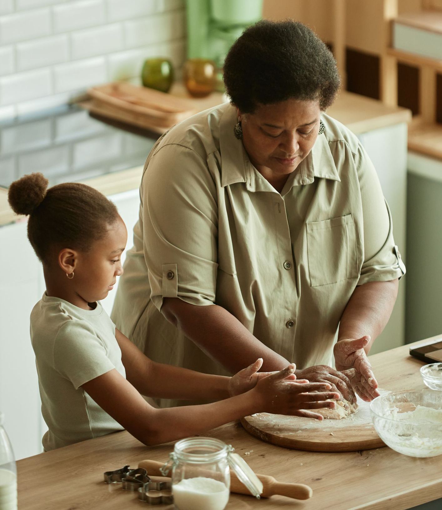 A woman and a little girl are preparing food in a kitchen.