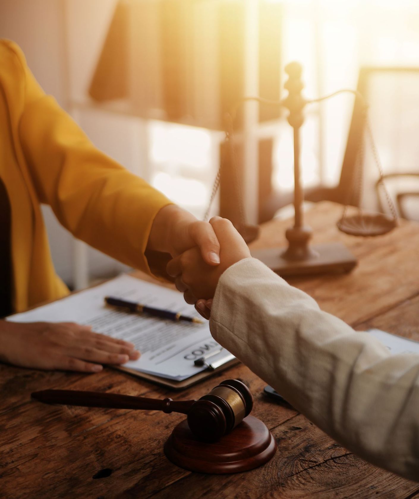 A woman is shaking hands with a judge while sitting at a wooden table.