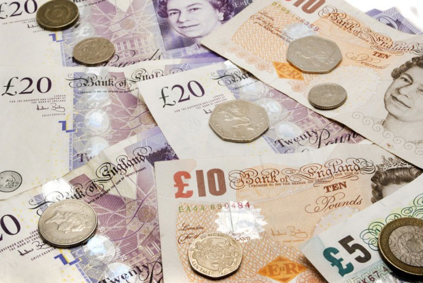 British pound banknotes and coins scattered on a surface