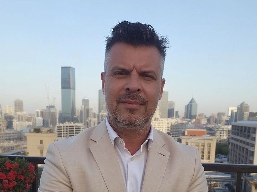 Man in light jacket, city skyline background.