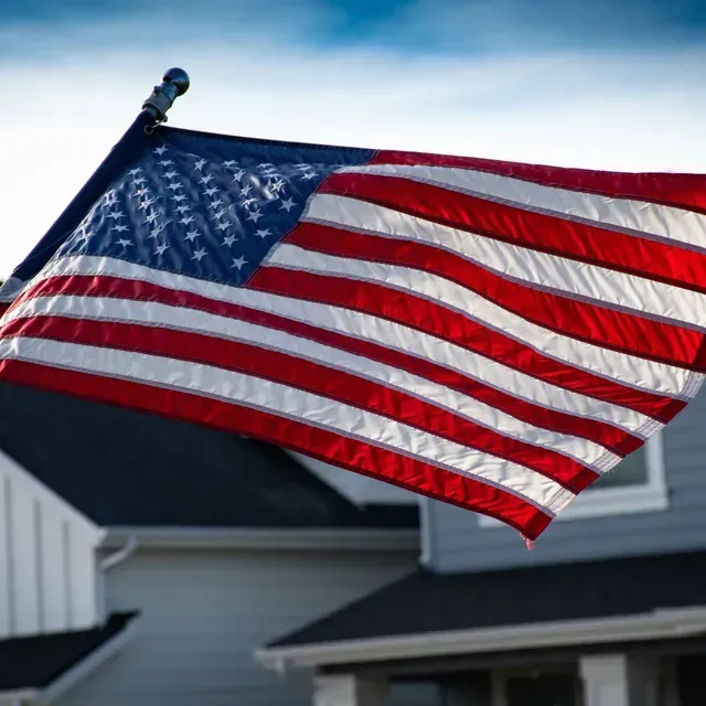 An american flag is flying in front of a house