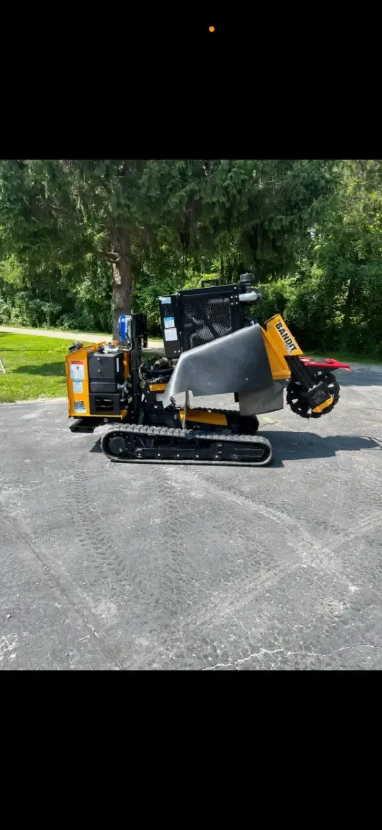 A small yellow and black tractor is parked in a parking lot.