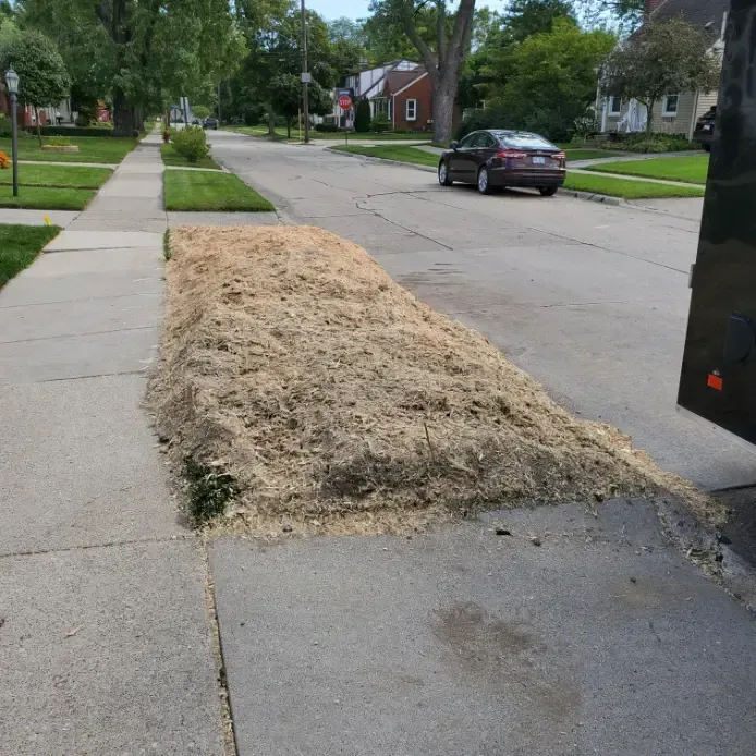 A car is driving down a street next to a pile of dirt