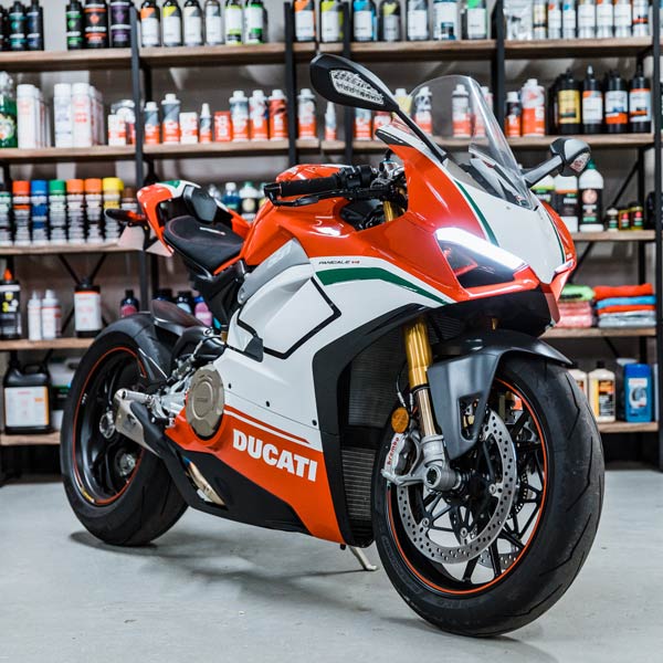 An orange and white ducati motorcycle is parked in a garage