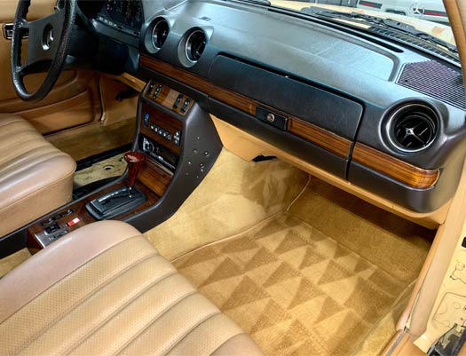 The interior of a car with tan seats and a black dashboard
