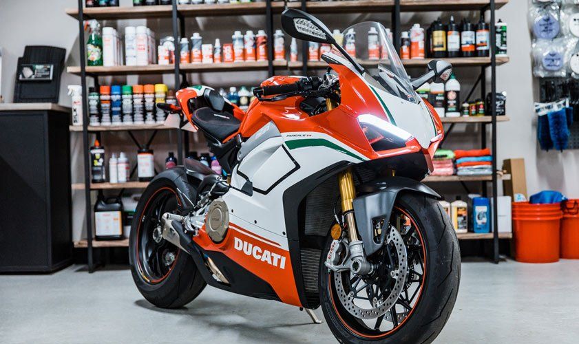 A red and white ducati motorcycle is parked in a garage.