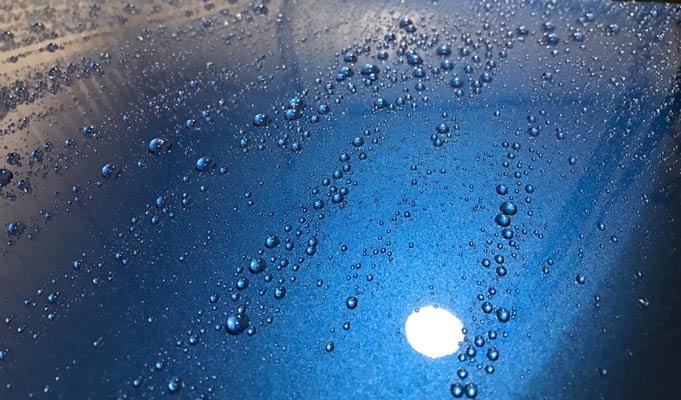 A close up of water drops on a blue surface.