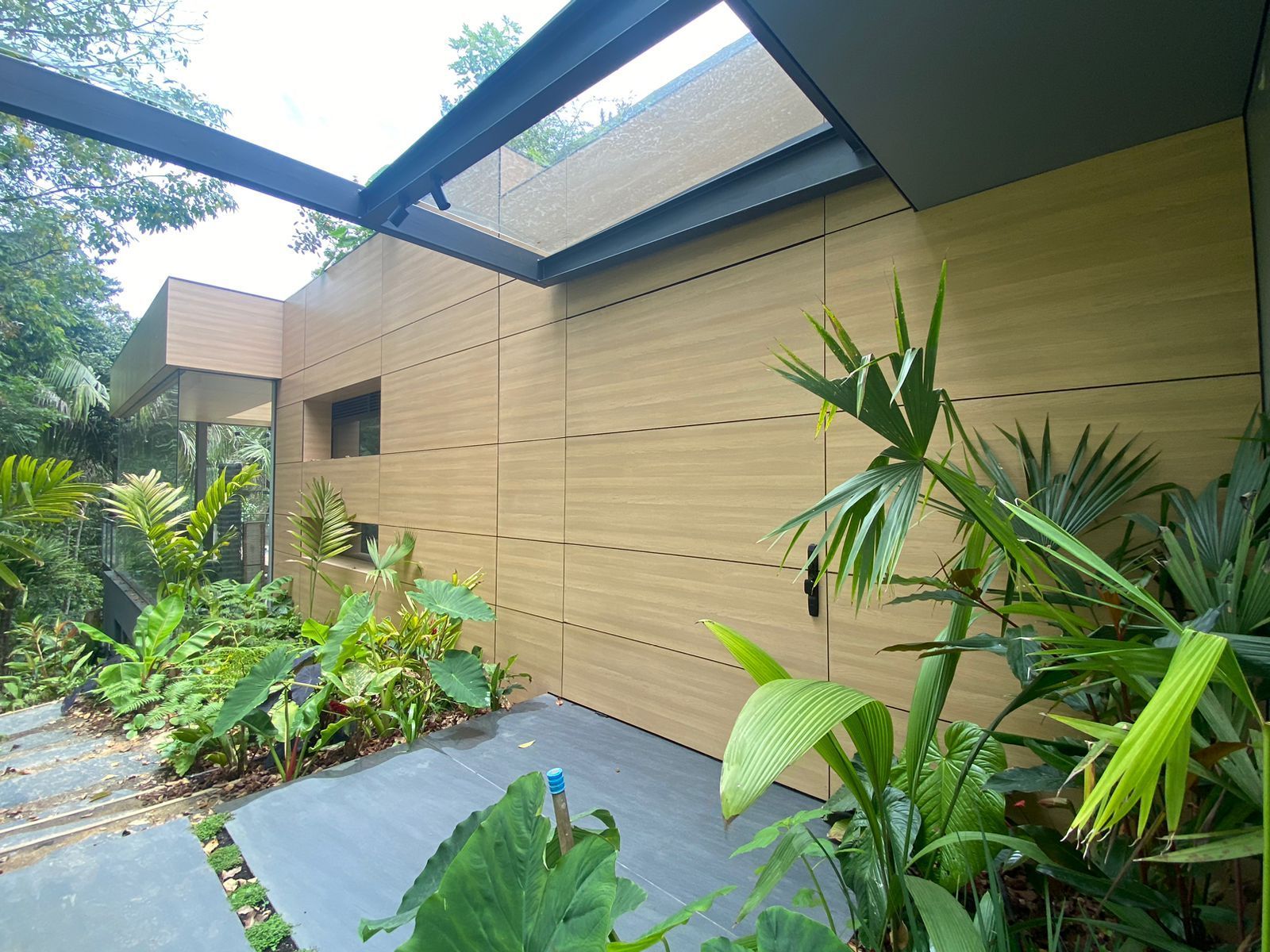 Una casa con muchas plantas y árboles al frente.