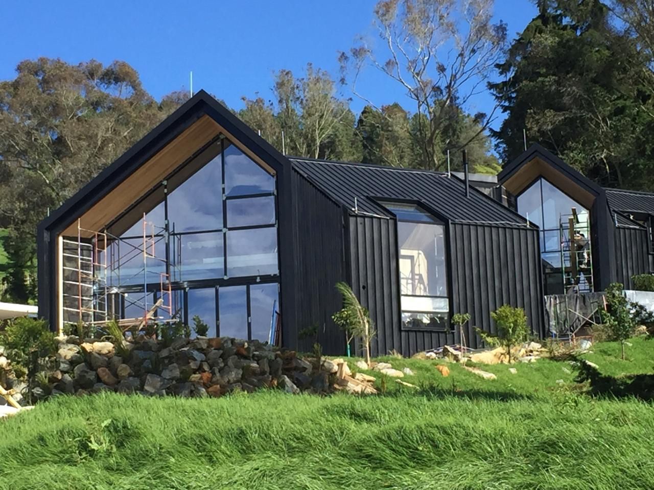 Una casa con muchas ventanas está situada en la cima de una colina cubierta de hierba.