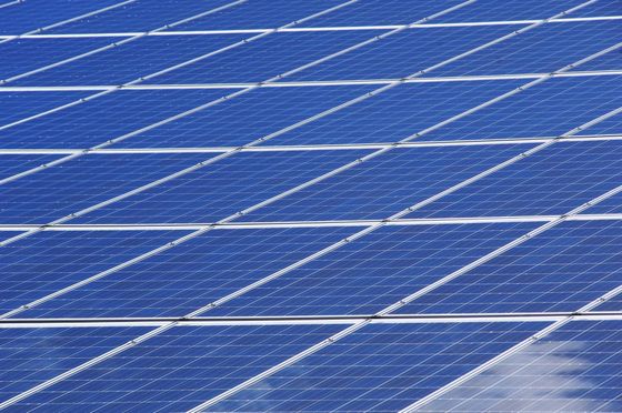 A row of blue solar panels against a blue sky