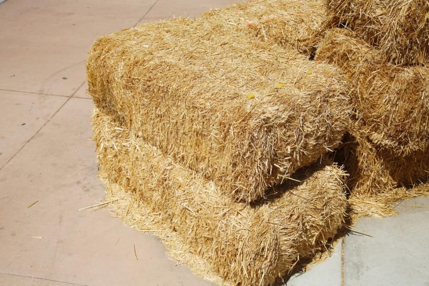 A Pile of Hay Bales Stacked on Top of Each Other on A Tiled Floor — Kempsey Produce & Saddlery in Kempsey, NSW