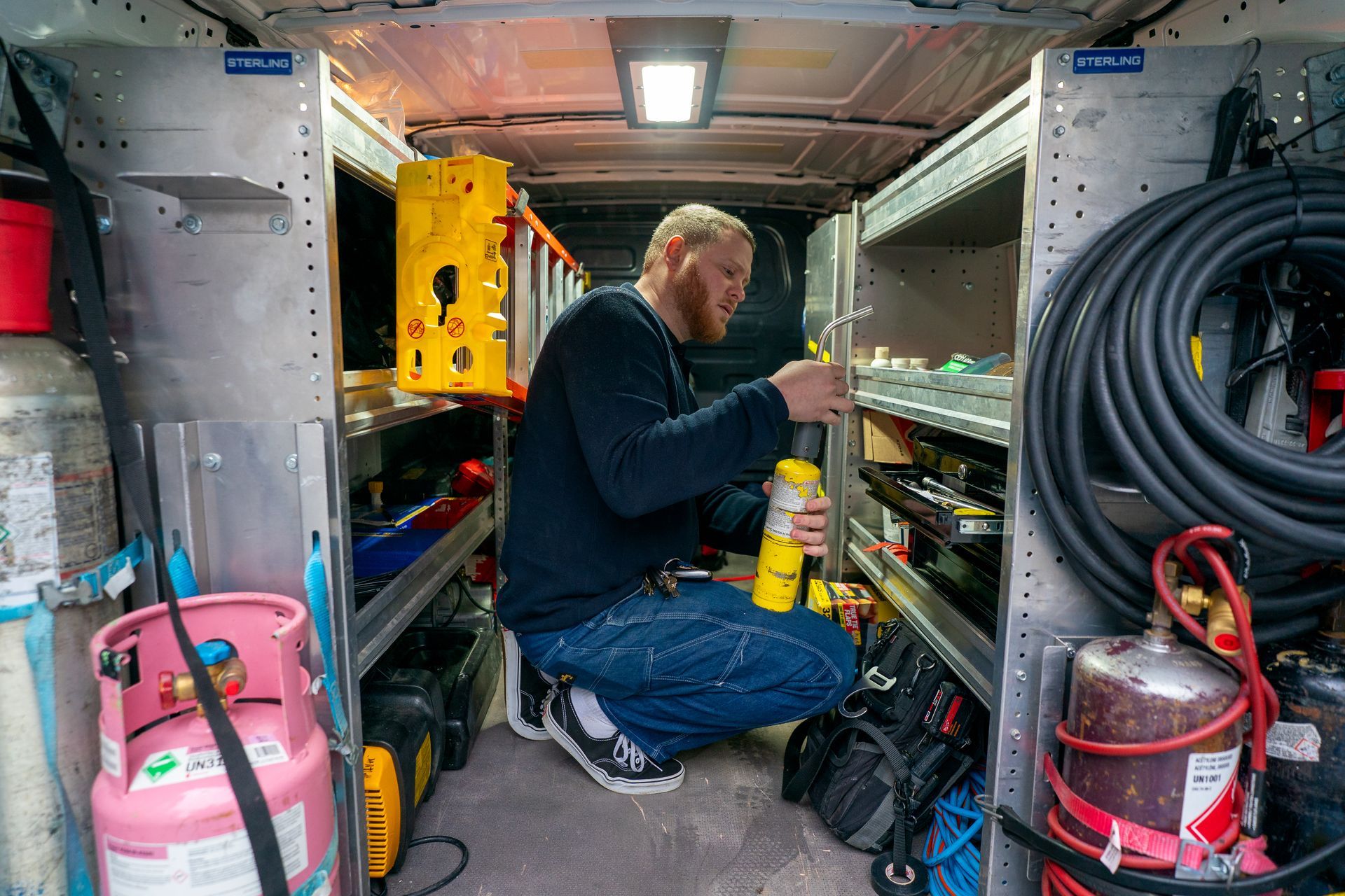 Air conditioner unit outside a brown house near a wooden deck and foliage.